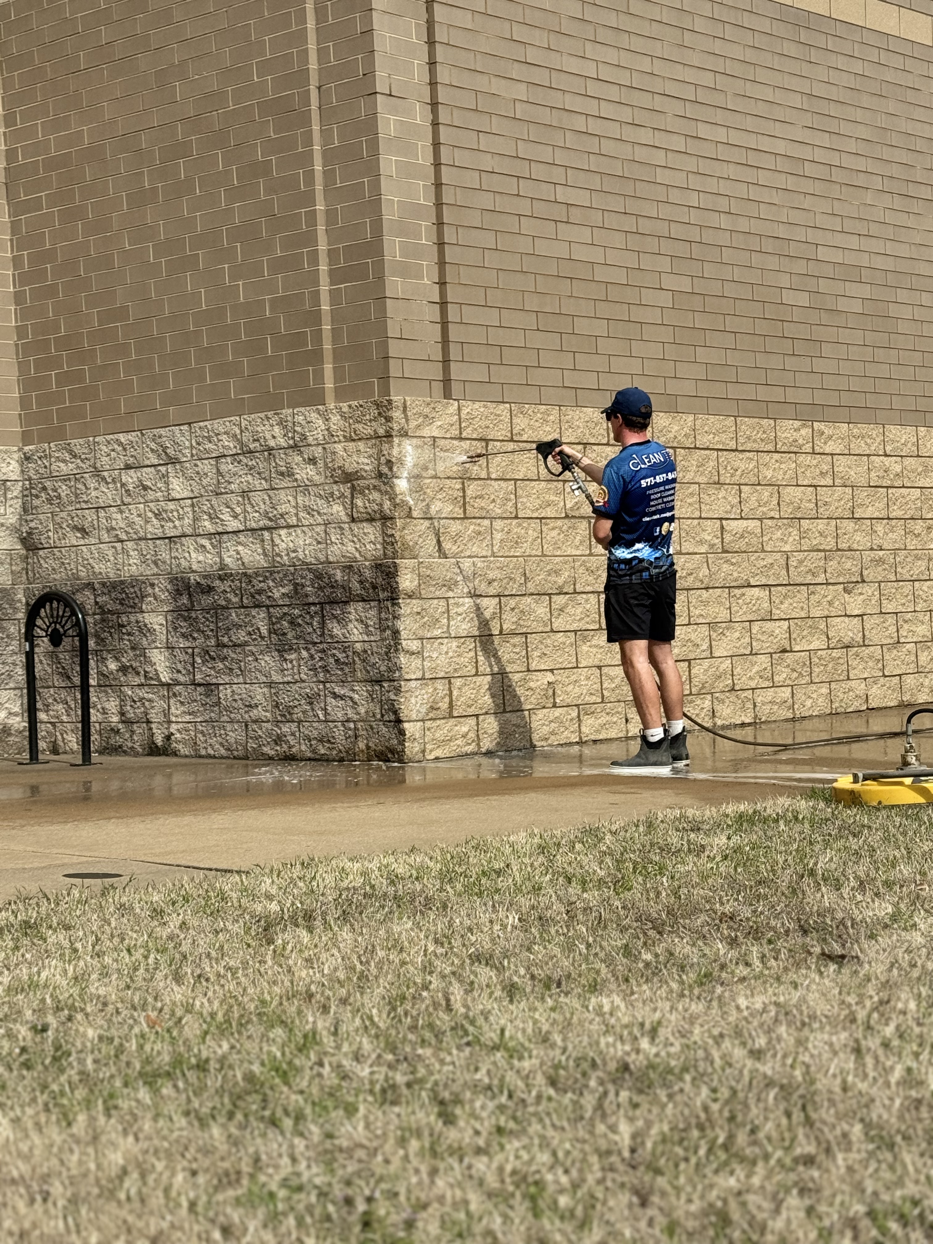 Clean Tek technician pressure washing a commercial building